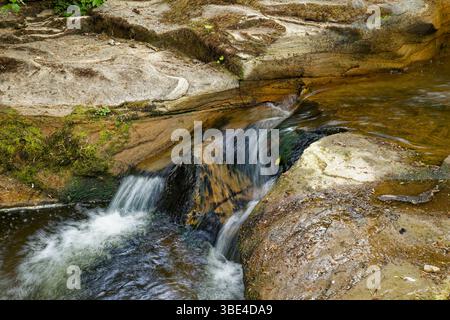 Water flows gently over smooth rocks of a river bed. Stock Photo
