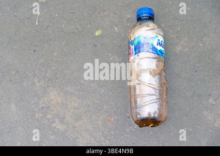 Bali, Indonesia - Dec 28, 2024: Bottle of Aqua water is laying on the ground. The bottle is empty and has a blue cap Stock Photo