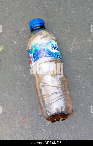 Bali, Indonesia - Dec 28, 2024: Bottle of Aqua water is laying on the ground. The bottle is empty and has a blue cap Stock Photo