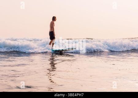 Surfer on longboard rides on fun ocean wave in Bali Stock Photo