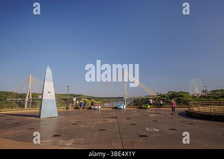 Puerto Iguazu, Misiones, Argentina - May 18th, 2025: Tourists walking along the Three Borders Landmark. Stock Photo