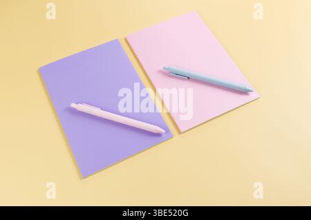 Top view of pink and purple notebooks, pink and blue pens on yellow background. School, office wallpaper. Flat lay, copy space. Stock Photo