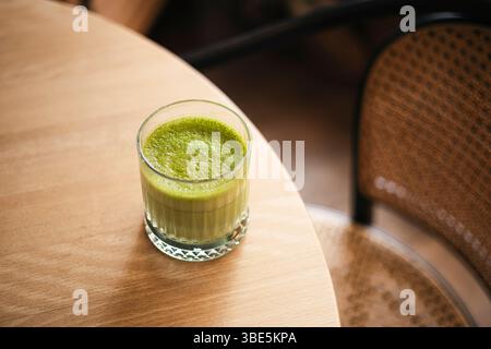 Top view of a freshly prepared matcha tea in a clear glass, served on a wooden tabletop. Stock Photo