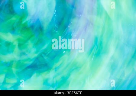 A captivating abstract image featuring soft waves of blue and green hues blending together. The fluid motion and light swirls create a soothing and ca Stock Photo