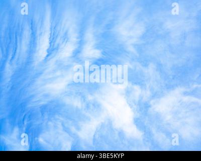A tranquil sky with wispy white clouds set against a backdrop of deep blue, evoking a sense of calm and peace. The light clouds create a beautiful con Stock Photo