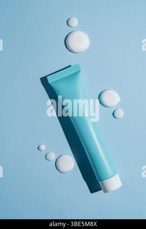 A sleek cosmetics package sits elegantly on a blue background, accented by smooth, artistic smears of white cream. The scene embodies modern beauty co Stock Photo