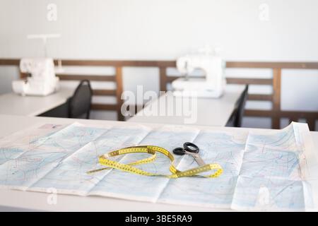 A sewing workshop featuring essential tools including scissors, a tape measure, and sewing pattern. Sewing machines are visible, highlighting a space Stock Photo