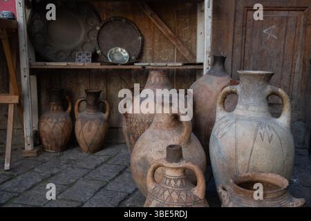 A collection of ancient clay jugs and pots displayed on a cobblestone floor in Fez, Morocco. The pottery features intricate patterns and earthy tones, Stock Photo