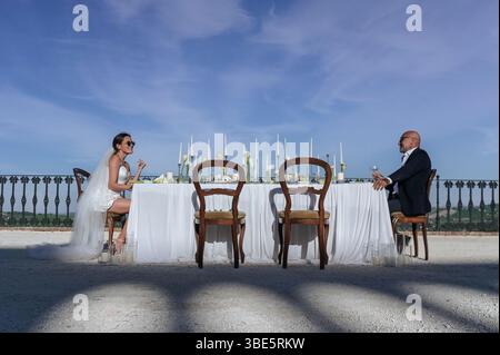 A picturesque wedding scene unfolds in an ancient villa in Treia, Macerata. The bride and groom are seated at an elegantly decorated outdoor table und Stock Photo
