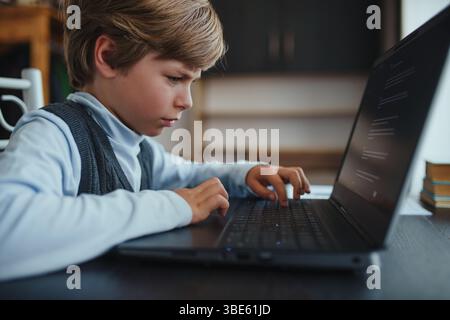 Cute boy learning to work on laptop at home Stock Photo
