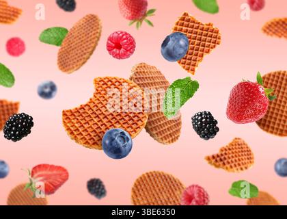 Tasty Dutch waffles, fresh berries and mint flying on pink gradient background Stock Photo