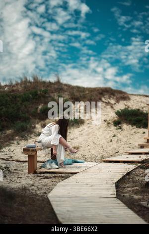 woman in white clothes dancing with blue cloth on the beach Stock Photo