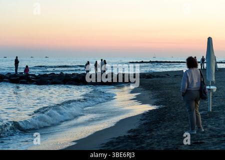 Rome, Italy. 27th May, 2025. People on the beach at sunset watch the passage of the Italian Navy training ship Amerigo Vespucci off the coast of Lido di Ostia in Rome. (Credit Image: © Marcello Valeri/ZUMA Press Wire) EDITORIAL USAGE ONLY! Not for Commercial USAGE! Stock Photo