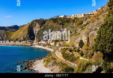 Taormina, Sicily, Italy - February 15, 2023: Panoramic view of Taormina shore at Ionian sea with Castello Saraceno castle, Giardini Naxos and Villagon Stock Photo