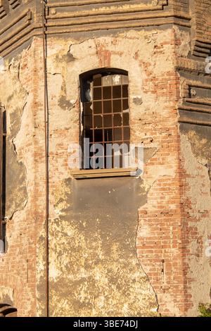 Old damaged wall with peeling plaster, red bricks detail and window, a rustic urban decay background Stock Photo