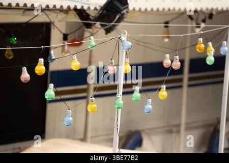 Colorful String Bulbs Hanging Against Outdoor Backdrop Stock Photo