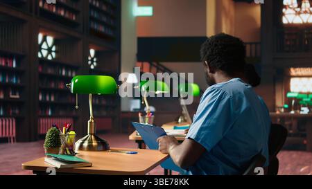 Future nurses studying anatomy class notes in a university library, reviewing courses and preparing for exams. Black med school students working together for their medical education. Camera A. Stock Photo
