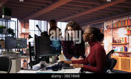 Teamworking engineers coding advanced AI algorithm and machine learning models enhancing automation. Employee talking with coworker in artificial intelligence Silicon Valley workspace, camera B Stock Photo