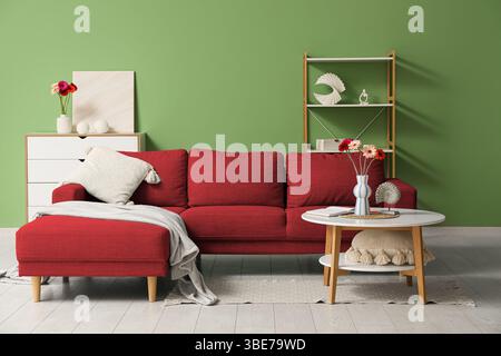 Red sofa with fresh gerbera flowers in interior of living room Stock Photo