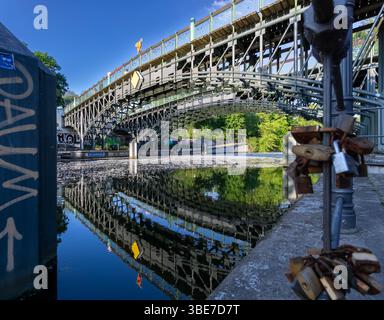 Lichtenstein Bridge over Berlin’s Landwehr Canal with metal love locks in the foreground and reflections on the calm water on a sunny spring day. Stock Photo