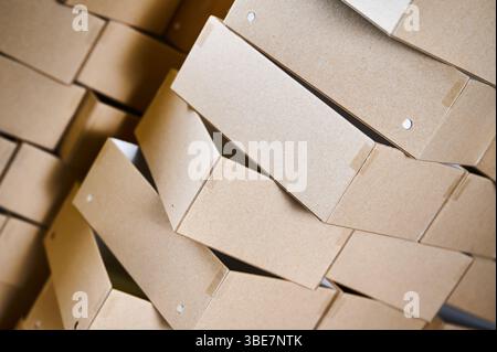 Stacked cardboard box blanks ready for assembly in a bustling manufacturing facility Stock Photo