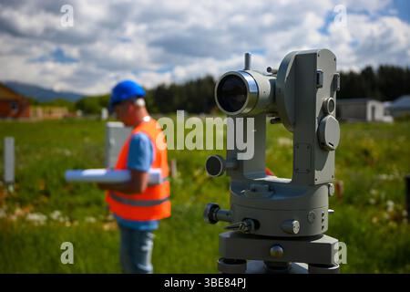 Surveyor using theodolite, a precision optical instrument, for accurate land measurement and surveying on a construction site. Stock Photo