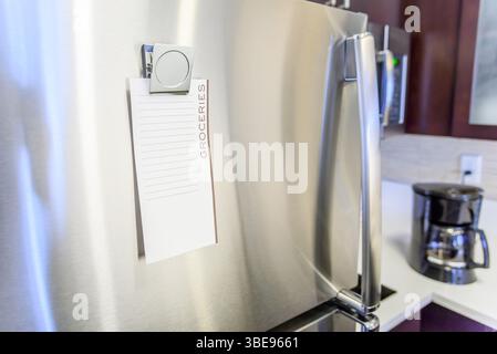 Glose up of a blank grocery shopping list on the door of stainless steel fridge in a kitchen Stock Photo