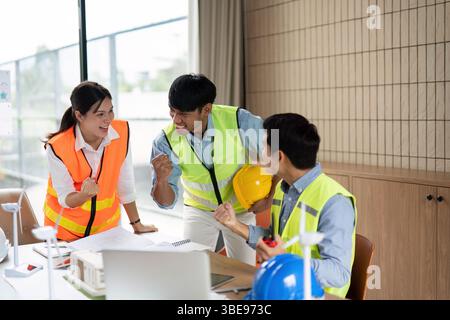 Green Tech Team Celebration. Engineers celebrating a successful project in a collaborative environment. Stock Photo