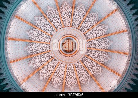 Intricate Islamic dome ceiling with radial symmetry, detailed arabesque floral patterns, and golden ornamental accents, captured from directly below i Stock Photo