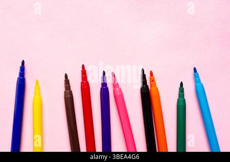 Colorful markers arranged on a pink background with copy space. Stock Photo