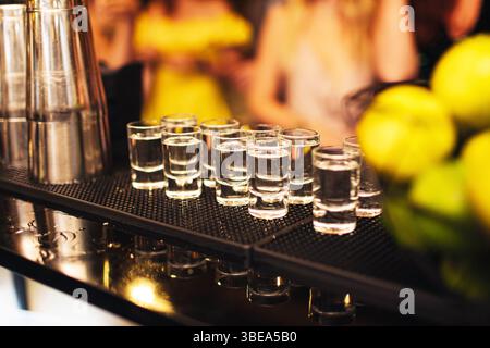 Shot glasses on bar counter. Nightlife and celebration concept. Alcohol drinks in row. Party background. Festive social event. Blurred lights. Stock Photo