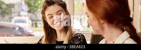 Two young women enjoy studying together, smiling as they share ideas in a cafe, banner Stock Photo