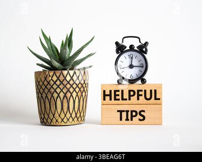 Helpful tips symbol. Wooden blocks with words Helpful tips. Beautiful white background with alarm clock and succulent plant. Business and Helpful tips Stock Photo