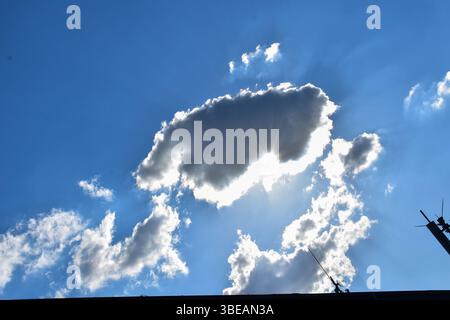 Antennas rise toward a sky lit by sunrays breaking through scattered clouds, highlighting the contrast between human-made structures and nature. Stock Photo