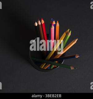 Set of colored pencils in a basket on a black background, isolated. back to school Stock Photo