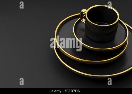 A set of black and golden ceramic plates and cup on a black background Stock Photo