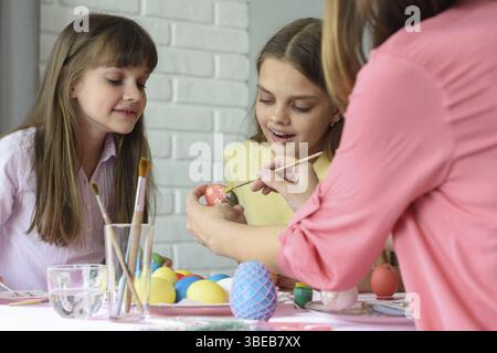 Mom shows girls how to paint Easter eggs beautifully Stock Photo