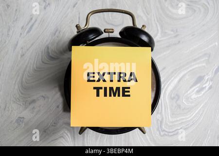 Concept of Extra time write on sticky notes isolated on Wooden Table. Stock Photo