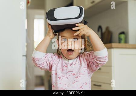 Toddler girl with vr glasses at home. Learning, watching movie, playing games. Future technologies. VR Stock Photo