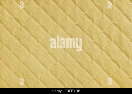 Checkered, diamond stitching pattern, yellow quilted fabric background. Blanket or puffer jacket, stitch rhombus texture close up, macro. Wallpaper, b Stock Photo