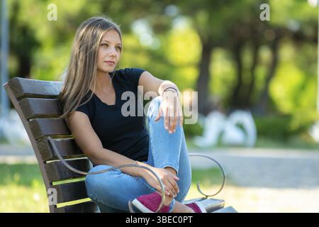 Maedchen sitzen auf einer Bank im Park, Nahaufnahme Stock Photo