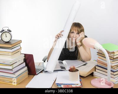 Tired student sitting at the table and put a figure to the head Stock Photo