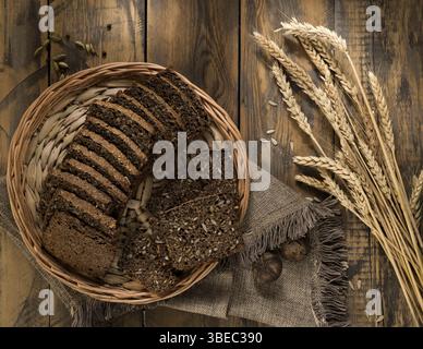 Sliced rye bread in a wicker tray and spikelets on wooden surface Stock Photo