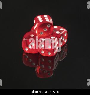 Group of red playing dice on a black background with reflection, isolated Stock Photo
