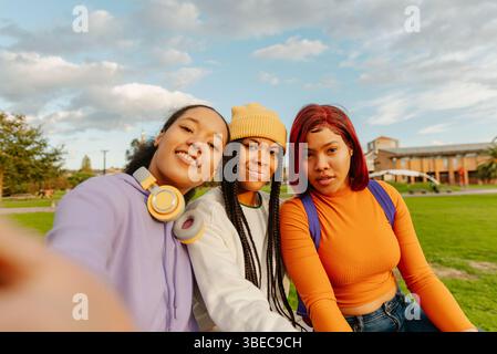 A heartwarming image of three cheerful Latin girls taking a selfie on a campus, capturing the essence of youthful friendship and diversity Stock Photo