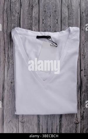 flat law of white V-neck t-shirt folded with label on vintage gray wood Stock Photo