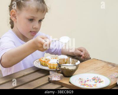 Girl puts focus on confectionery glaze Easter cupcakes Stock Photo