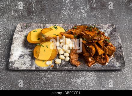 Delicious peruvian dish featuring spicy grilled tripe, fried potatoes with huancaína sauce, and cancha corn, served on a marble tray Stock Photo