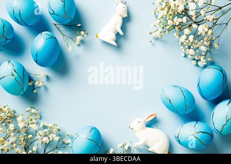 Blue Easter eggs, bunny, flowers on light blue background. Happy Easter greeting card template. Flat lay, top view, copy space. Stock Photo