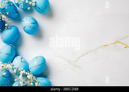 Flat lay composition with blue Easter eggs and flowers on marble stone table. Easter background. Stock Photo